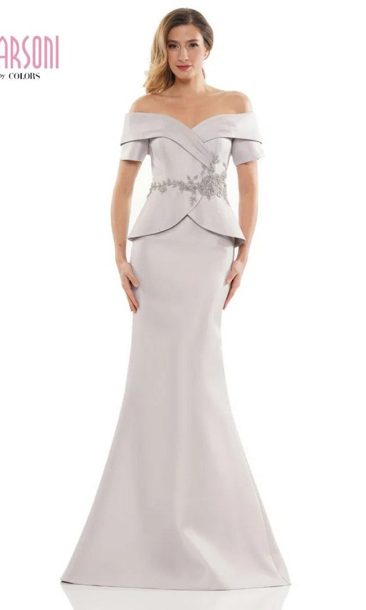 A woman in the Marsoni MV1144 long formal dress—a taupe, off-the-shoulder mermaid gown with floral waist embellishments—stands against a white background.